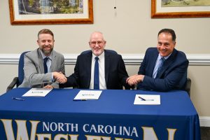 Photo of Dr. Evan D. Duff, NCWU President, Dr. Lew K. Hunnicutt, NCC President, Dr. Steve Ellis, NCPS Superintendent shaking hands. Positioned left to right. 